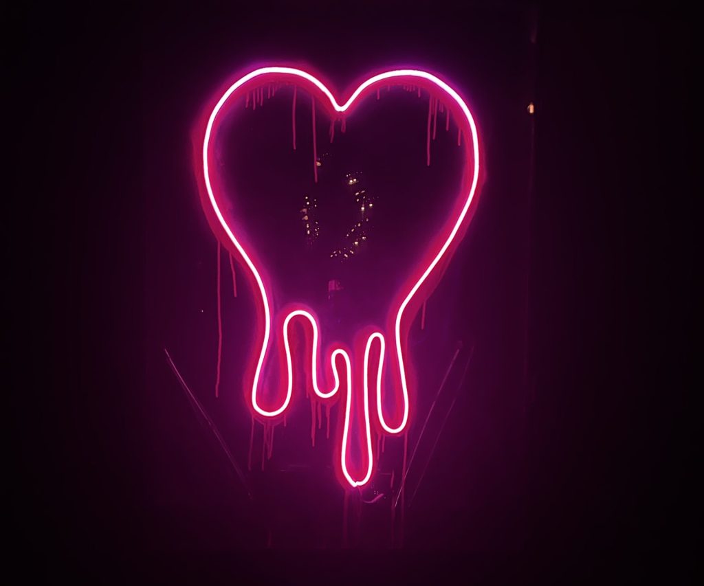 Dripping neon pink heart sign glowing in darkness — desire and shame essay, 49Grey