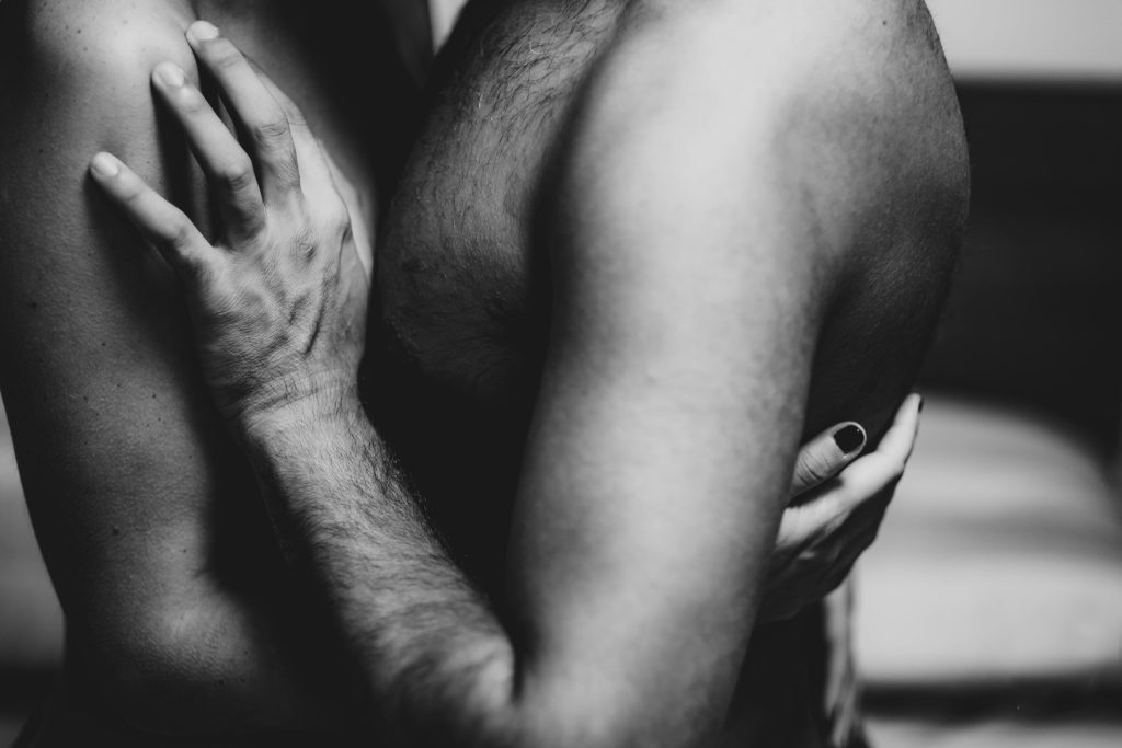 Black-and-white close-up of hands and arms in an intimate in-person embrace — unscripted connection essay, 49Grey
