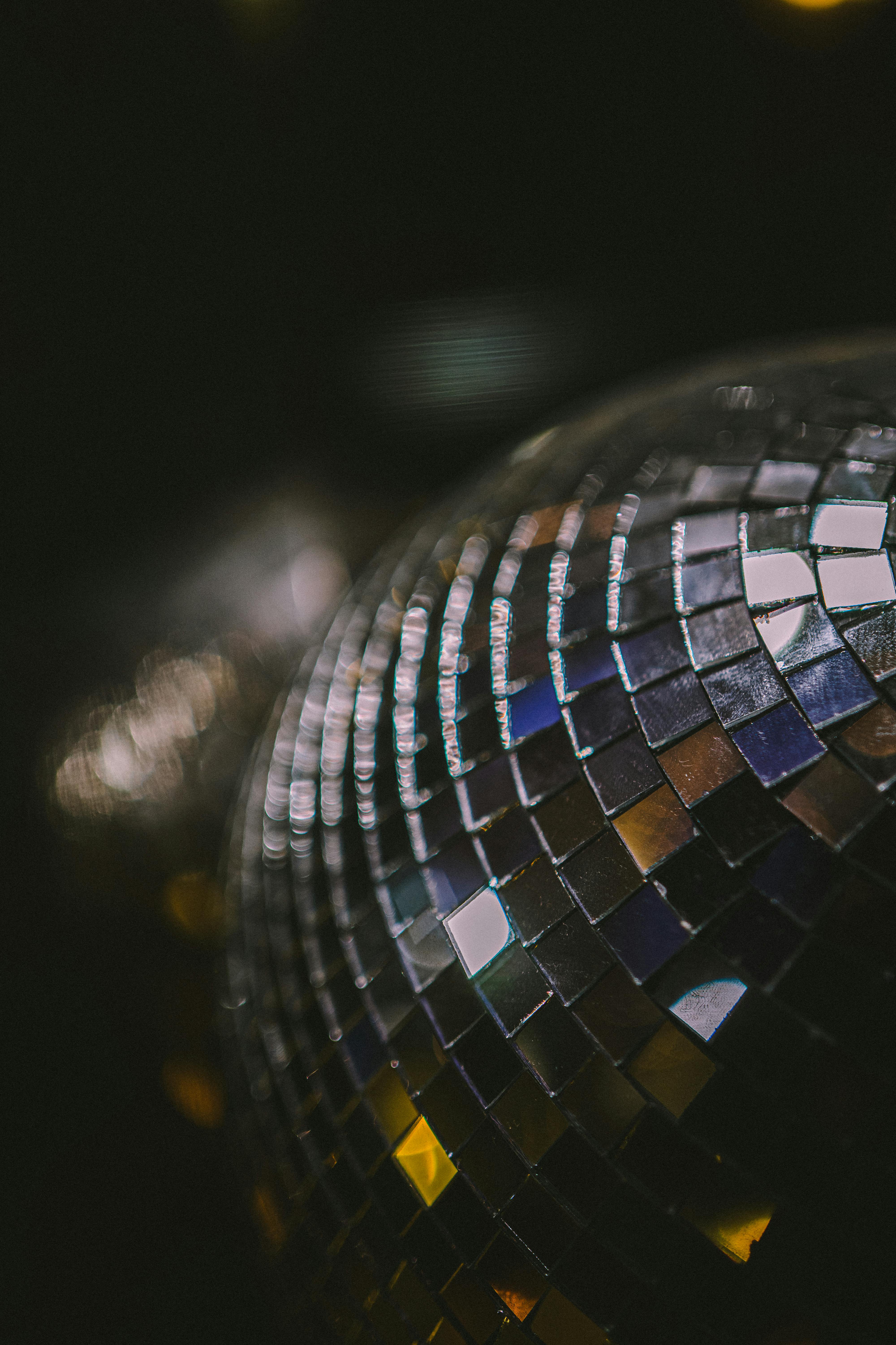 Close-up of a mirrored disco ball catching warm bokeh light — gay bar nightlife essay, 49Grey
