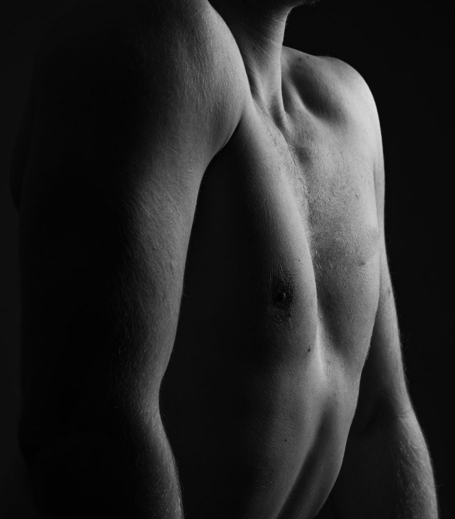Black-and-white close-up of bare shoulder and collarbone in shadow — masturbation shame reclamation essay, 49Grey